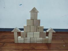 a wooden block tower sitting on top of a hard wood floor next to a wall