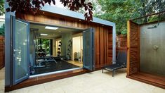 an outdoor gym is shown in the middle of a backyard with wood and glass walls