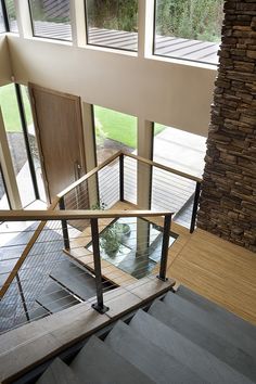 an aerial view of a stair case with glass railings and wood handrails