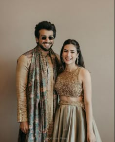 a man standing next to a woman wearing a dress and smiling at the camera with her arm around him