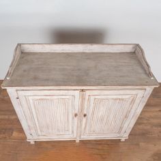 an old white wooden cabinet sitting on top of a hard wood floor