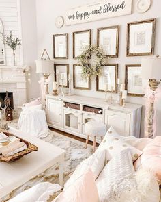 a living room filled with white furniture and pictures on the wall above it's fireplace