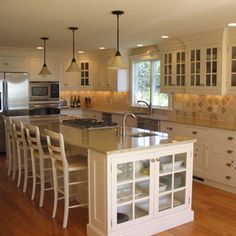 a large kitchen with white cabinets and wooden floors