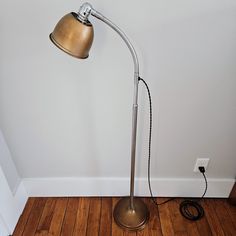 a floor lamp with a cord plugged in to it on top of a hard wood floor