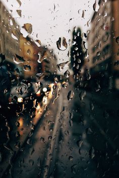 rain drops on the window and buildings in the background as seen from inside a car