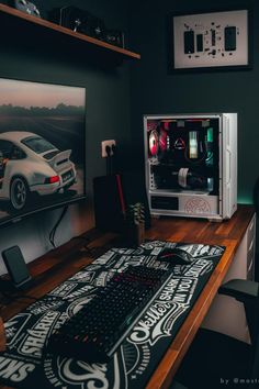 a desk with a computer on top of it next to a painting and mouse pad