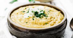 a close up of a bowl of food on a table with spoons and napkin