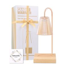 a gold lamp next to a white box with a yellow ribbon on it and a card