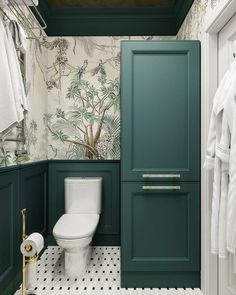 a bathroom with green cabinets and wallpaper on the walls, along with a toilet