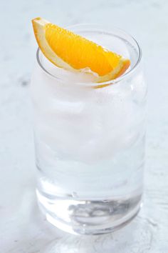 an orange slice sitting on top of a glass filled with water