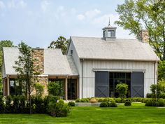 a large white barn with gray shutters and windows