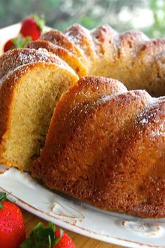 a bundt cake on a plate with strawberries around it and one slice cut out