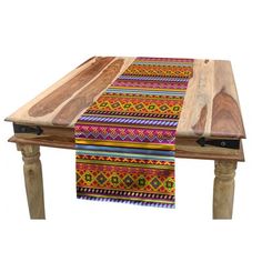 a wooden table topped with a multicolored striped placemat on top of it