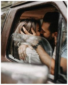 a man and woman are kissing in the back seat of a car while they're inside