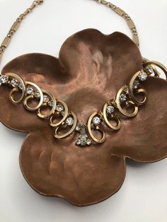 "This elegant rhinestone choker necklace is very unique. It could possibly be an unsigned Kramer of New York from the 1950's. It has bars of gold tone metal separated by rhinestones. Next is a section with gold tone swirls that go over rows of brilliant rhinestones. At the bottom middle is a cluster 4 round and one pear shaped rhinestones. There is one tiny stone that is a little clouded. There are no missing rhinestones. The gold tone medal is in very good condition with minimal or no discoloration. It is adjustable to fit tightly on the neck or to lay at the décolletage. This necklace would be lovely for the bride to wear or just to wear to any gala.  This choker necklace is a beautiful example of fine vintage jewelry.  In excellent vintage condition.  Dimensions: 15\"-17\" adjusts at cl Vintage Diamond Necklace With Accents, Vintage Diamond Necklace With 17 Jewels For Evening, Vintage Diamond Necklace With Diamond Accents, Vintage Diamond Wedding Necklace, Vintage Rhinestone Jewelry For Vintage Events, Vintage Diamond Necklaces For Evening, Vintage Diamond Necklace For Evening, Vintage Rhinestone Necklace For Vintage Events, Vintage Gold Rhinestone Necklace With Sparkling Stones