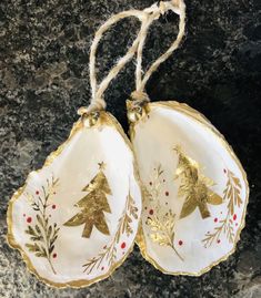 two christmas ornaments hanging from twine on a granite counter