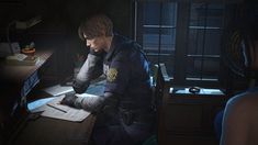 a young man sitting at a desk in the dark