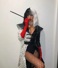 a woman dressed in black, white and red poses for the camera while holding a wand