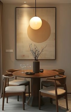 a dining room table with chairs and a vase on the top, in front of a painting