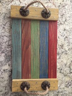 a wooden wall hanging with rope and knobs on top of a marble countertop