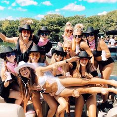 a group of women in bikinis and cowboy hats posing for a photo on a boat