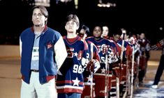 a group of men standing next to each other on top of a hockey field at night