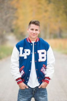 a young man standing in the middle of a road wearing a blue and white jacket