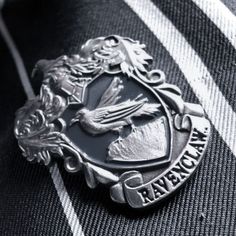 a close up of a tie with a bird on the crest and words ravenclaw