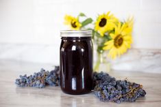 a glass jar filled with liquid sitting on top of a table next to sunflowers