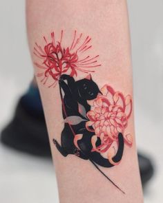 a black cat with red flowers on it's leg is holding a flower in its paws