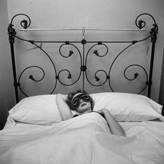 a woman laying in bed with a mask on her face