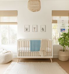 a white crib with a blue blanket in the corner next to a potted plant