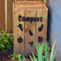 a wooden composting box with the word compost written in black on it