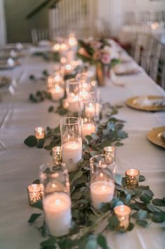 a long table with candles and greenery on it