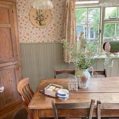 a wooden table sitting in front of a window next to a vase filled with flowers