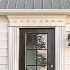 a cat sitting on top of a window sill next to a black front door