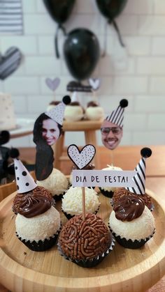 some cupcakes are sitting on a wooden plate with pictures and decorations in the background