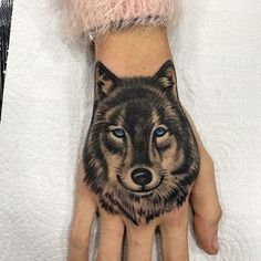 a hand with a wolf tattoo on it