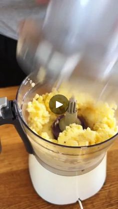 a food processor with mashed potatoes and olives in it on a wooden table