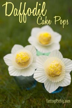 three white paper flowers with yellow dots on them sitting in the grass and text overlay reads daffodil cake pops