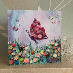 a card with flowers and butterflies on it sitting on a table next to some glass vases