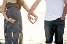 a pregnant woman standing next to a man holding the hand of her husband's belly