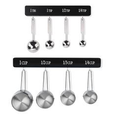 four measuring spoons hanging from hooks on a white wall with black and silver labels