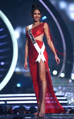 a woman in a red dress is walking down the runway