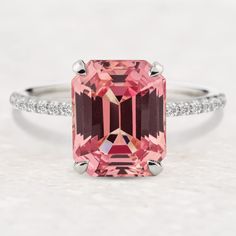 a pink tourmaline and diamond ring on a white surface with diamonds around it