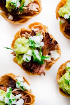 small appetizers with meat, guacamole and onions are arranged on a white surface