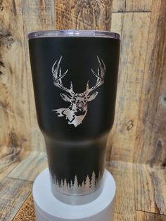 a black and white cup with a deer head on it sitting on top of a stand