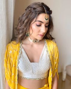 a woman in yellow and white outfit standing next to a window with her hands on her hips