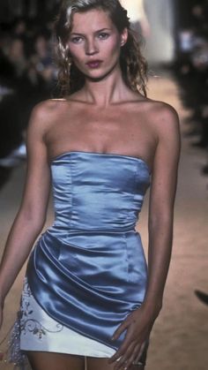 a model walks down the runway in a blue dress