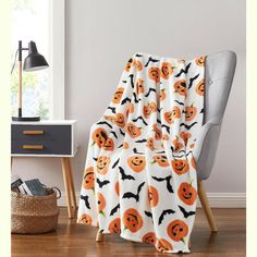 an orange pumpkin and bat pattern blanket on a chair